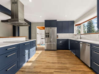 Experience modern living in this stunning kitchen featuring sleek navy blue cabinetry and pristine white countertops.