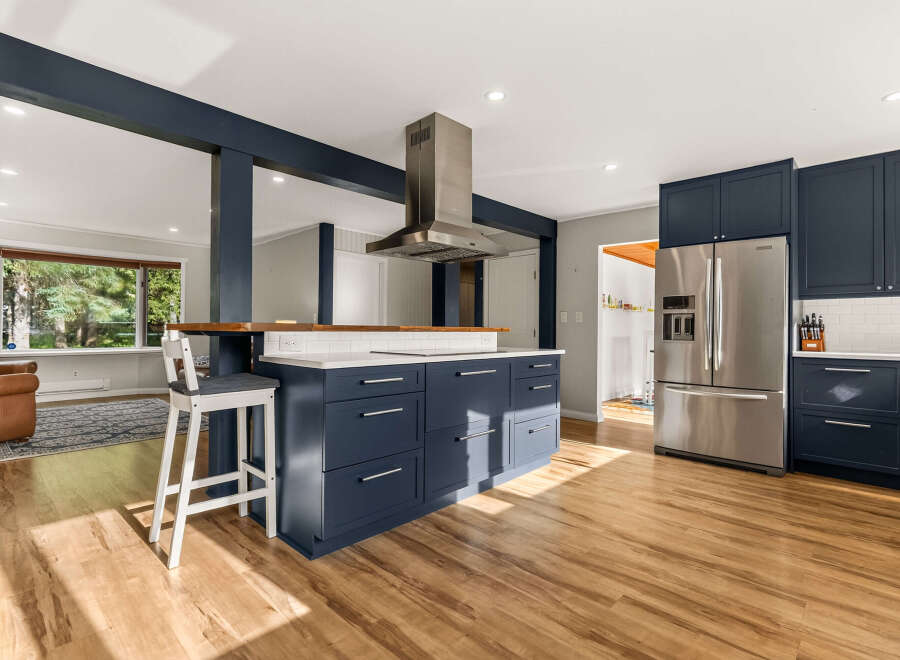Experience modern living in this stunning kitchen featuring deep navy cabinetry and a spacious island with a butcher block countertop.