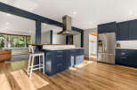 Experience modern living in this stunning kitchen featuring deep navy cabinetry and a spacious island with a butcher block countertop.