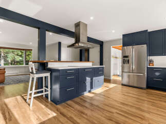 Experience modern living in this stunning kitchen featuring deep navy cabinetry and a spacious island with a butcher block countertop.