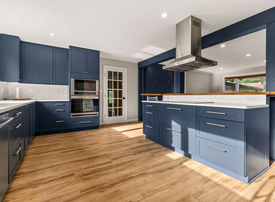 Experience the epitome of modern living in this stunning kitchen, featuring sleek navy blue cabinetry and gleaming white countertops.