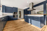Experience the epitome of modern living in this stunning kitchen, featuring sleek navy blue cabinetry and gleaming white countertops.