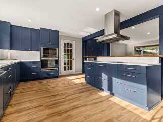 Experience the epitome of modern living in this stunning kitchen, featuring sleek navy blue cabinetry and gleaming white countertops.