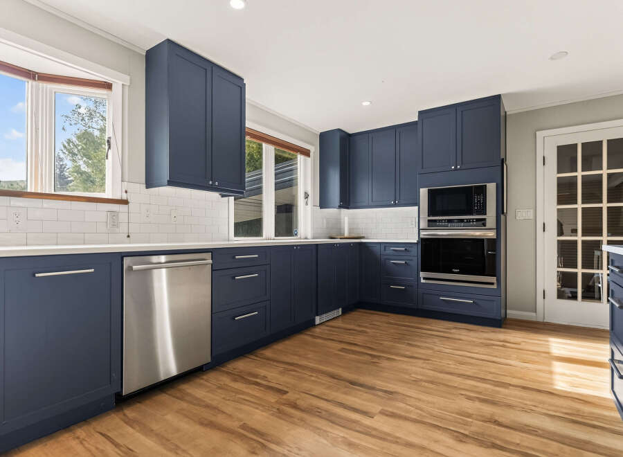 Discover this beautifully renovated kitchen featuring sleek navy blue cabinetry and modern stainless steel appliances.