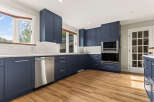 Discover this beautifully renovated kitchen featuring sleek navy blue cabinetry and modern stainless steel appliances.