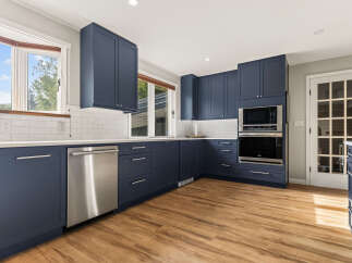 Discover this beautifully renovated kitchen featuring sleek navy blue cabinetry and modern stainless steel appliances.