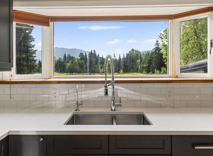 This stunning kitchen boasts a large bay window offering breathtaking mountain and forest views, perfect for enjoying your morning coffee.