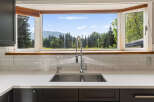 This stunning kitchen boasts a large bay window offering breathtaking mountain and forest views, perfect for enjoying your morning coffee.