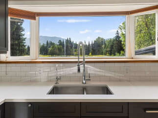 This stunning kitchen boasts a large bay window offering breathtaking mountain and forest views, perfect for enjoying your morning coffee.
