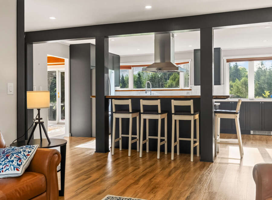 Experience seamless indoor-outdoor living with this stunning kitchen and dining area, featuring a sleek island with bar seating and ample natural light.