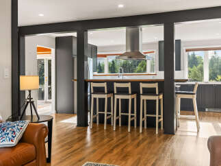 Experience seamless indoor-outdoor living with this stunning kitchen and dining area, featuring a sleek island with bar seating and ample natural light.