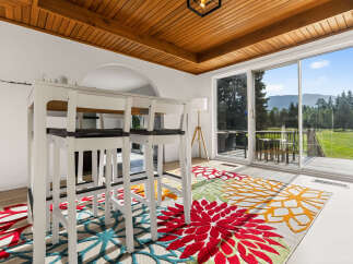Enjoy breathtaking mountain views from this spacious dining area, featuring a modern white bar table with stools perfect for casual meals.
