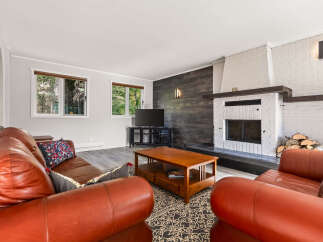 Cozy up by the brick fireplace in this inviting living room, featuring warm leather sofas and a rustic wood accent wall.