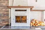 Cozy up by this stunning white brick fireplace, featuring a rustic wooden mantel and double glass doors for a clear view of the fire.