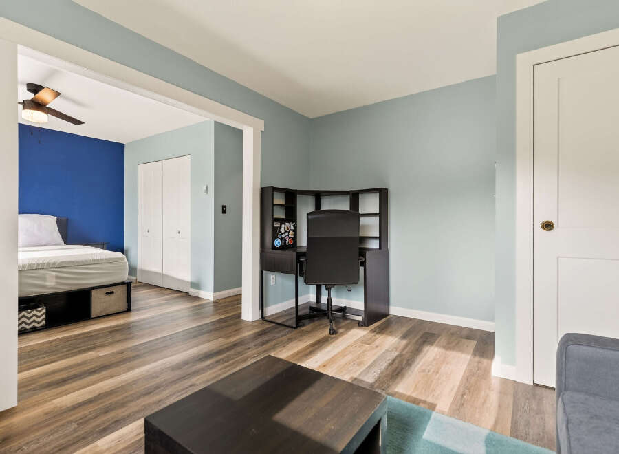 Discover a versatile living space with a dedicated home office area featuring a sleek desk and chair, perfect for remote work or study.