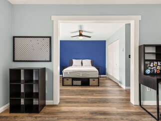 Discover a serene bedroom featuring a comfortable bed with storage drawers, complemented by a vibrant blue accent wall.