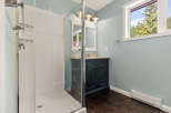 This charming bathroom features a spacious glass-enclosed shower with convenient shelving.