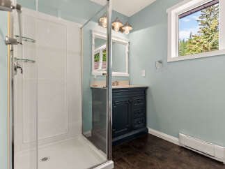 This charming bathroom features a spacious glass-enclosed shower with convenient shelving.