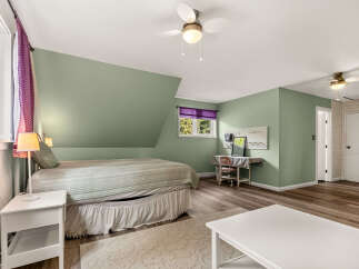 Discover this charming bedroom featuring a comfortable bed with a textured quilt and a decorative bed skirt.