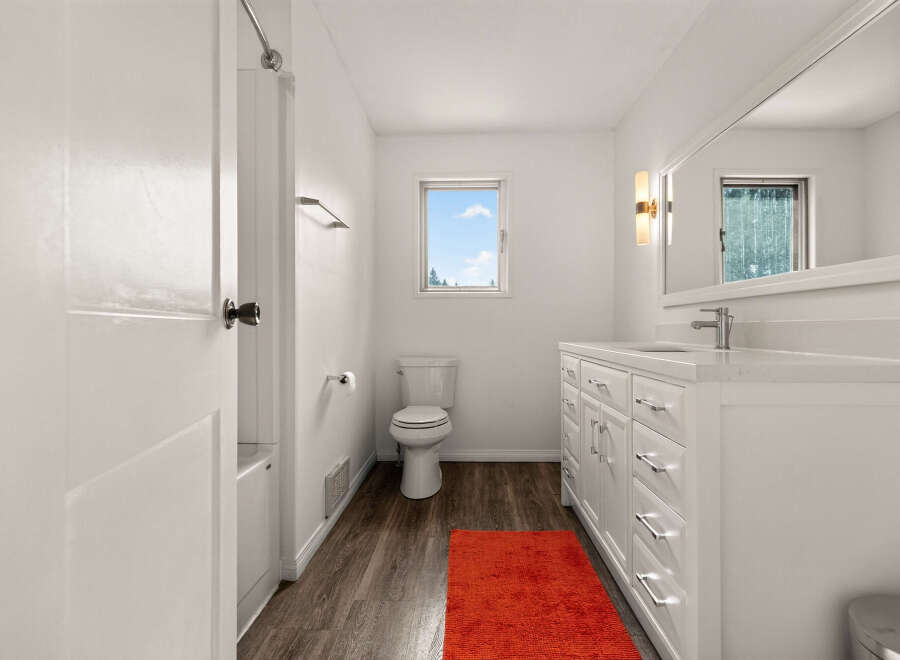 This bright and airy bathroom features a modern white vanity with ample storage and a sleek countertop.
