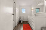 This bright and airy bathroom features a modern white vanity with ample storage and a sleek countertop.