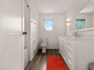 This bright and airy bathroom features a modern white vanity with ample storage and a sleek countertop.