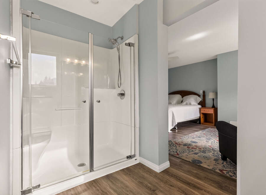 Experience modern comfort with this spacious walk-in shower, featuring sleek glass doors and a rainfall showerhead.