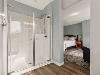 Experience modern comfort with this spacious walk-in shower, featuring sleek glass doors and a rainfall showerhead.