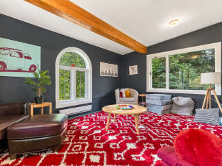 This cozy living room features a large red and white patterned rug, perfect for family gatherings or playtime.