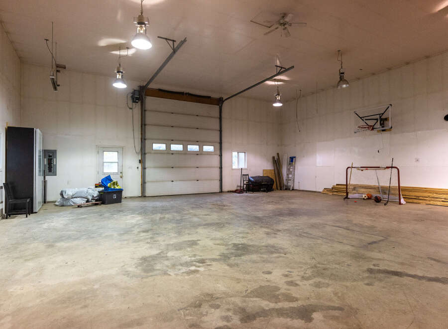 This spacious garage offers ample room for vehicles and storage, featuring a large overhead door for easy access.