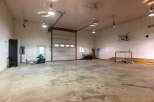 This spacious garage offers ample room for vehicles and storage, featuring a large overhead door for easy access.