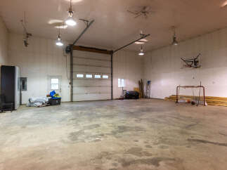 This spacious garage offers ample room for vehicles and storage, featuring a large overhead door for easy access.