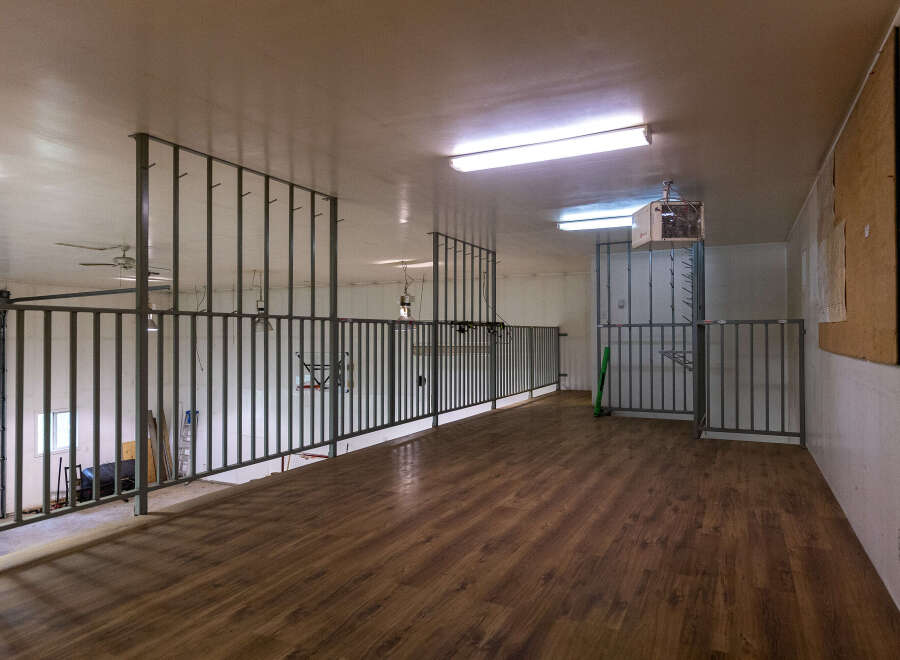 Explore this versatile loft space featuring a durable wood-look floor and sturdy metal railings, perfect for various uses.