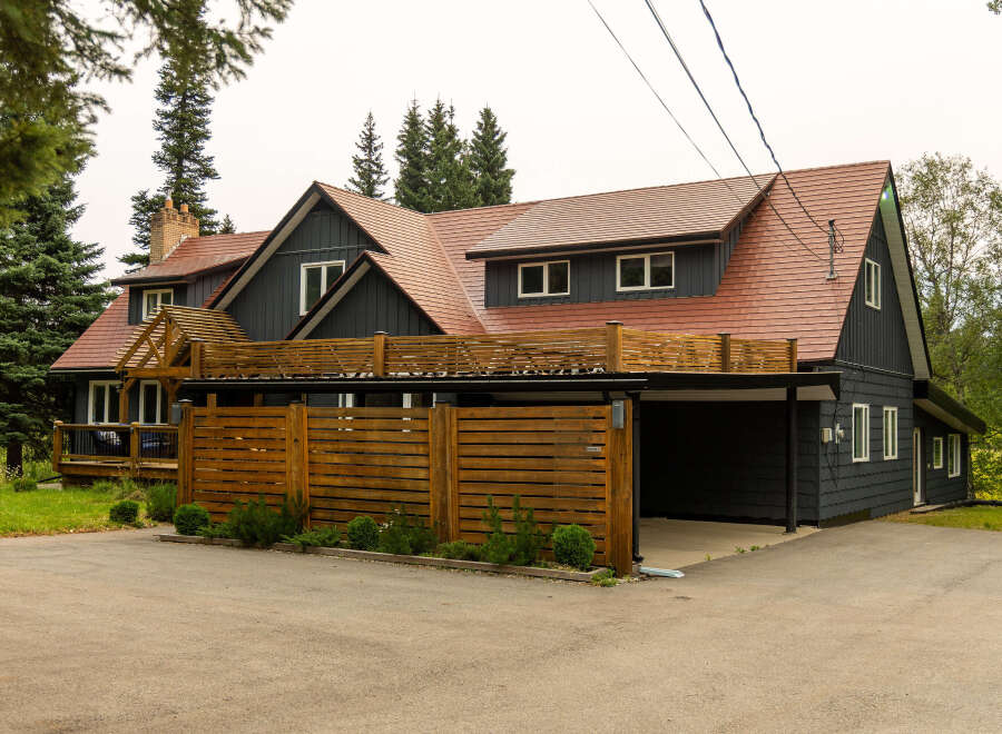 Discover this stunning dark-sided home featuring a durable, reddish-brown tiled roof and a modern wooden fence.