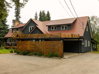 Discover this stunning dark-sided home featuring a durable, reddish-brown tiled roof and a modern wooden fence.