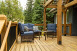 Enjoy outdoor living on this spacious wooden deck, complete with comfortable blue upholstered seating and a charming wicker coffee table.