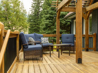 Enjoy outdoor living on this spacious wooden deck, complete with comfortable blue upholstered seating and a charming wicker coffee table.