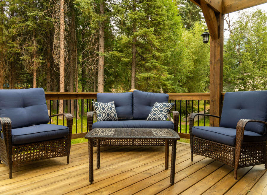 Enjoy the serene outdoors from this charming deck, featuring comfortable seating and a stylish coffee table.