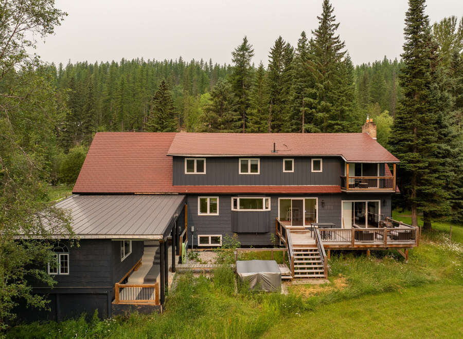 Nestled amidst a lush forest, this expansive home offers a serene retreat with its multi-level decks and balconies perfect for enjoying the surrounding nature.
