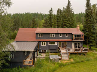 Nestled amidst a lush forest, this expansive home offers a serene retreat with its multi-level decks and balconies perfect for enjoying the surrounding nature.