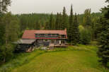 Nestled amidst a lush forest, this expansive home offers a serene retreat with its dark siding and warm red roof.