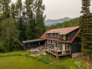 Nestled amidst lush greenery and towering trees, this charming home offers a serene mountain retreat.