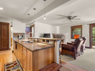 Experience comfortable living in this inviting space featuring a well-appointed kitchen with granite countertops and a spacious living area centered around a stone fireplace.