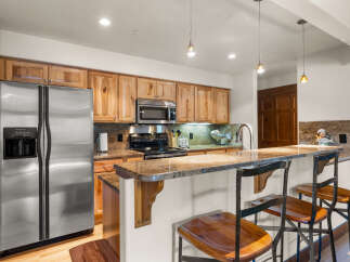 This spacious kitchen features beautiful light wood cabinetry and granite countertops, offering ample storage and a sleek workspace.
