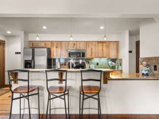 This kitchen features a sleek stainless steel refrigerator, a microwave, and a stovetop, all complemented by warm wooden cabinetry.