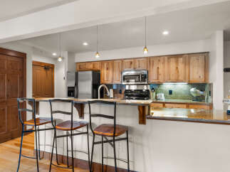 This charming kitchen features warm, natural wood cabinetry complemented by granite countertops and a convenient breakfast bar with seating.