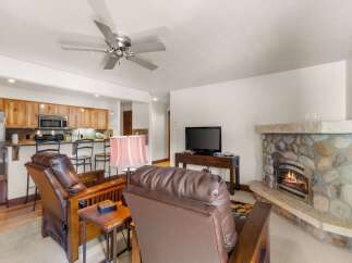 Cozy up by the stone fireplace in this inviting living room, perfect for relaxing after a day of adventure.
