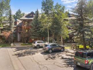 Discover this charming property featuring a multi-story building with rustic wood and stone accents, surrounded by mature trees.