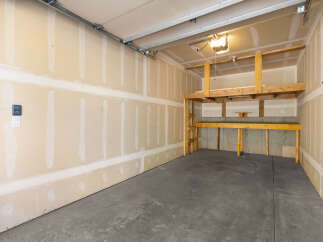 This spacious garage offers ample storage solutions with its built-in wooden shelving units, including a two-tiered system perfect for organizing tools and equipment.