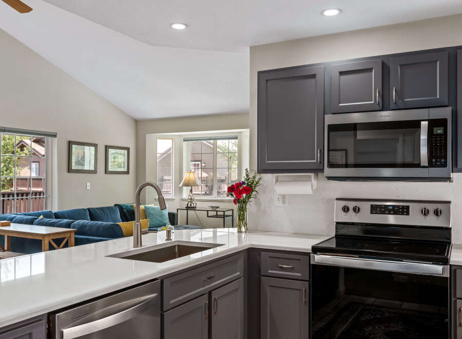 This modern kitchen features sleek gray cabinetry, a stainless steel microwave, and a smooth electric stovetop, perfect for any home chef.